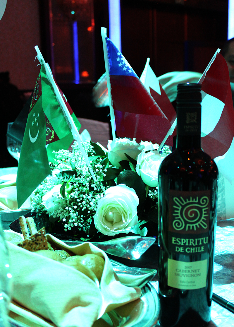 Table centrepiece of white roses and national flags with the evening's wines, UNAS 40th Anniversary Gala Dinner